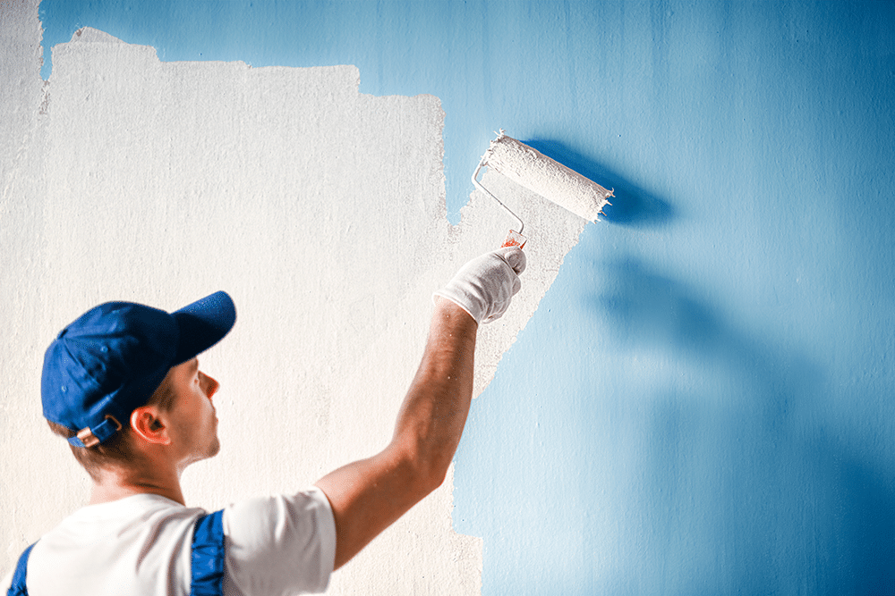 Artisan peintre à Toulouse appliquant une couche de peinture blanche au rouleau